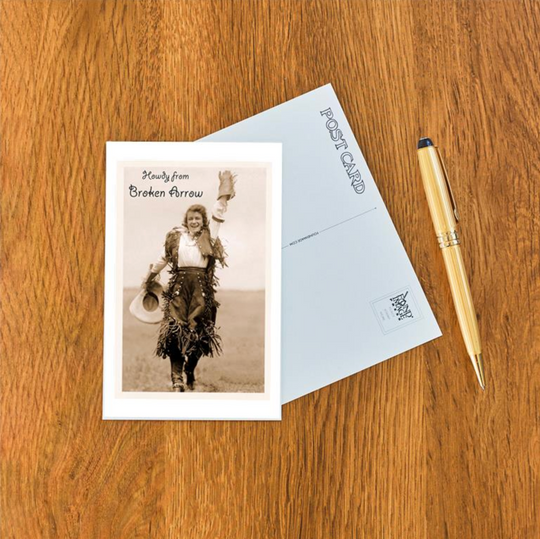 Nostalgic postcard with a vintage cowgirl waving and “Howdy from Broken Arrow” lettering.