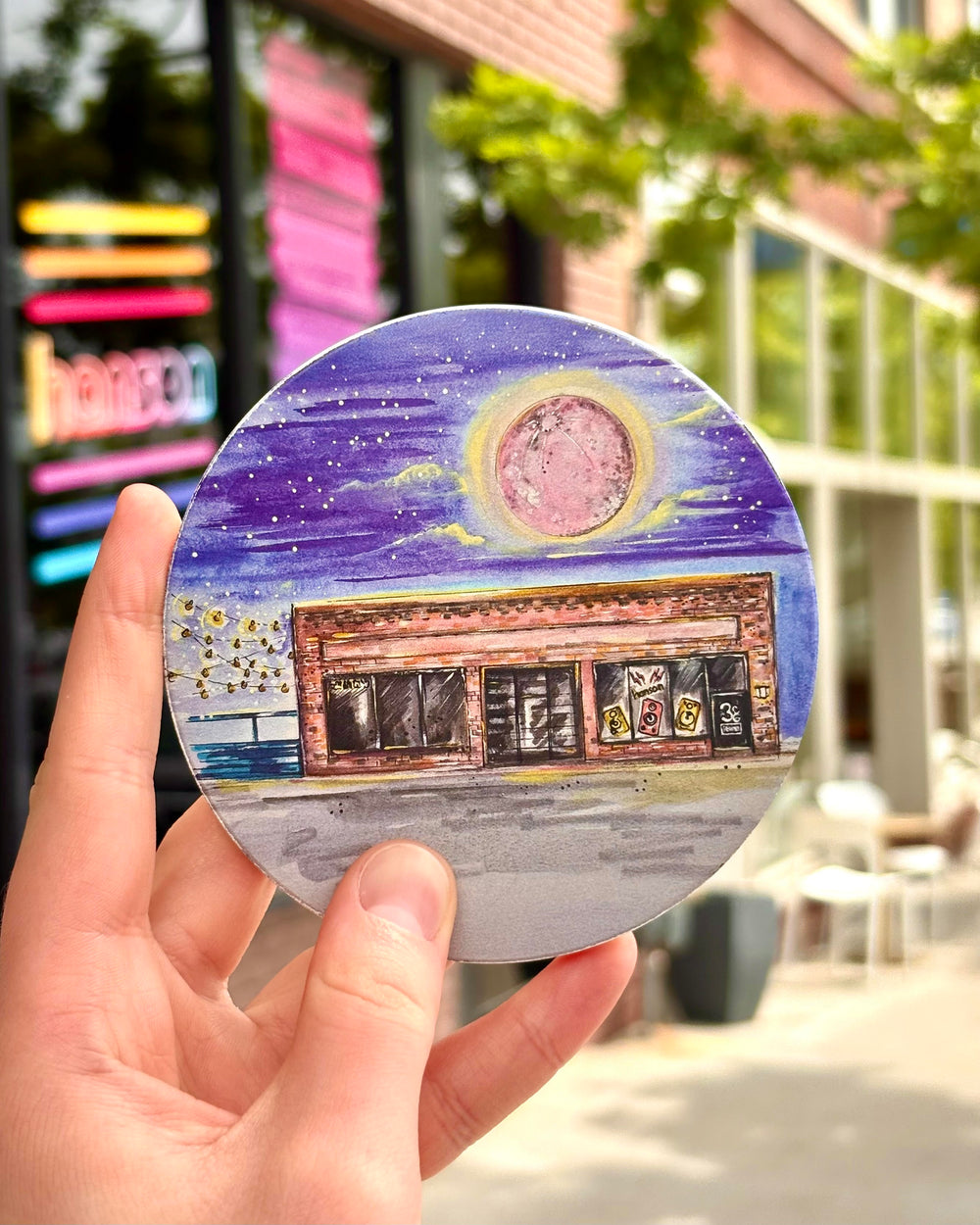 Person holding Hanson 3CG Studios coaster outside the Tulsa recording studio – collectible band merch for fans