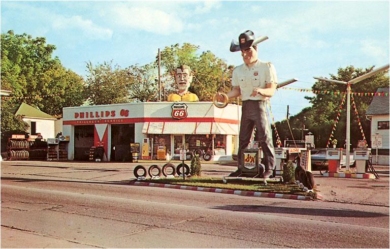 Route 66 Gas Station with Giant Man Holding Tire Postcard