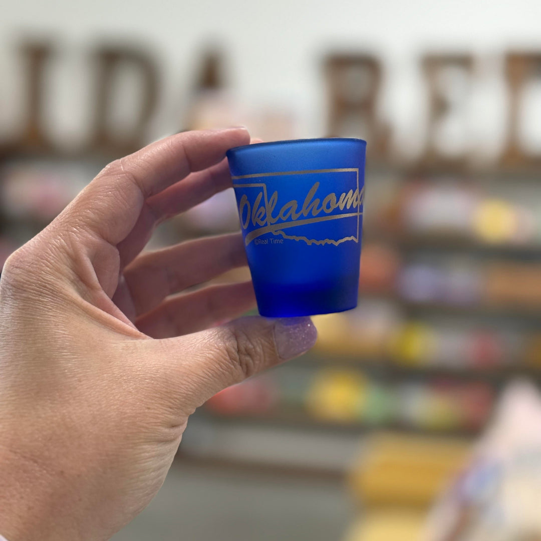 State-themed blue shot glass featuring Oklahoma in gold script