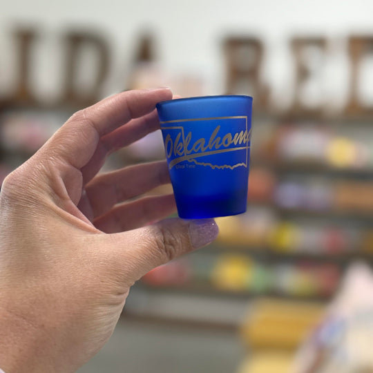 State-themed blue shot glass featuring Oklahoma in gold script
