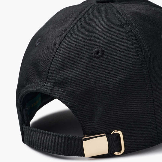 Close-up of the back of a black baseball cap with an adjustable strap and a gold-tone metal buckle, shown on a white background.