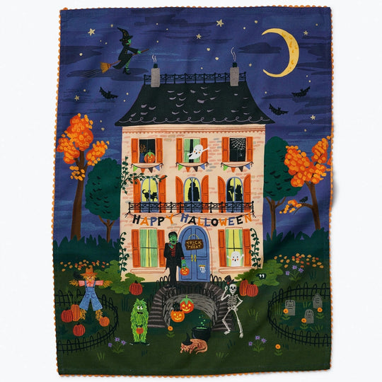 Halloween-themed dishtowel with a haunted house and festive decorations.