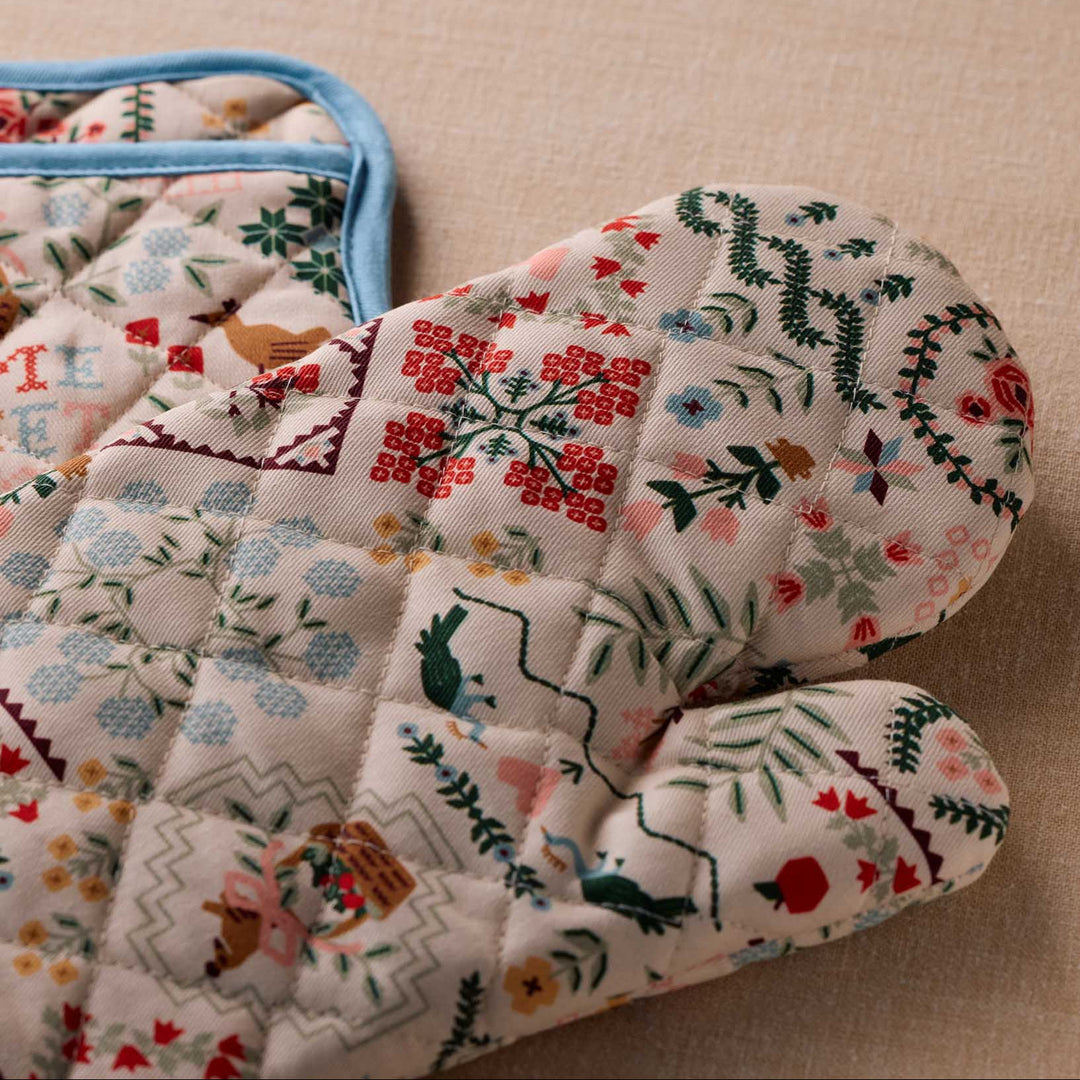 Pair of floral-patterned oven mitts on a beige surface