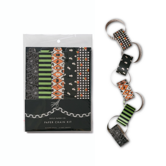 A Halloween-themed paper chain kit, shown both in its clear plastic packaging on the left and assembled on a white background on the right. The patterns include black and white spiderwebs, green and black stripes, orange and black geometric designs, and black and white polka dots.