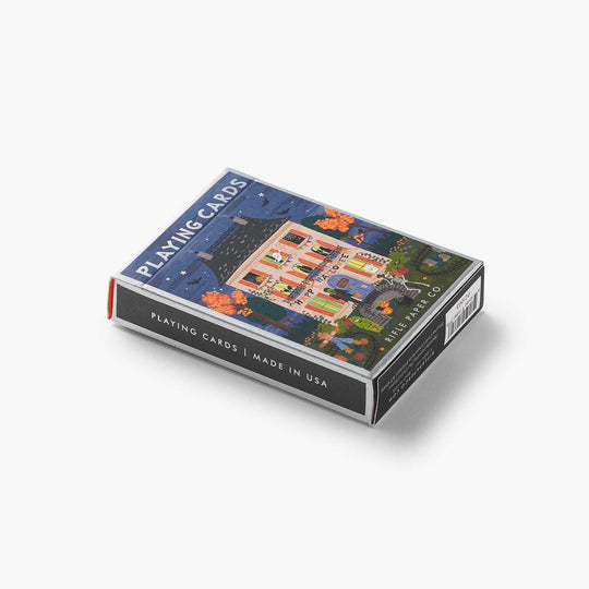 A boxed deck of playing cards with a dark illustrated cover showing a house and autumn leaves, photographed on a clean white background.