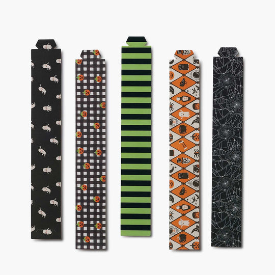 Five Halloween-themed paper strips arranged vertically on a light gray background. The patterns include white rabbits on black, black and white gingham with orange pumpkins, green and black stripes, orange and white diamond patterns with pumpkins and bats, and a black spiderweb design.