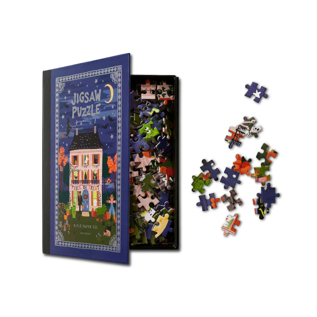 A boxed jigsaw puzzle set shown on a white background, with the illustrated puzzle box on the left, the open box of loose pieces in the center, and several scattered puzzle pieces on the right.