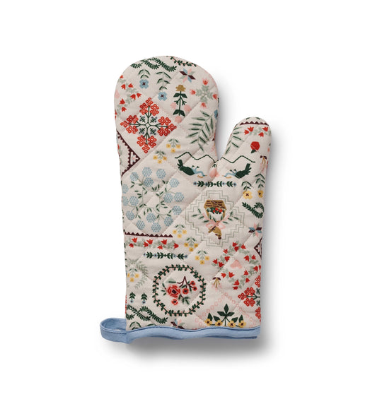 A quilted oven mitt featuring a patchwork design with a light blue fabric cuff at the bottom, shown on a white background with a soft drop shadow.