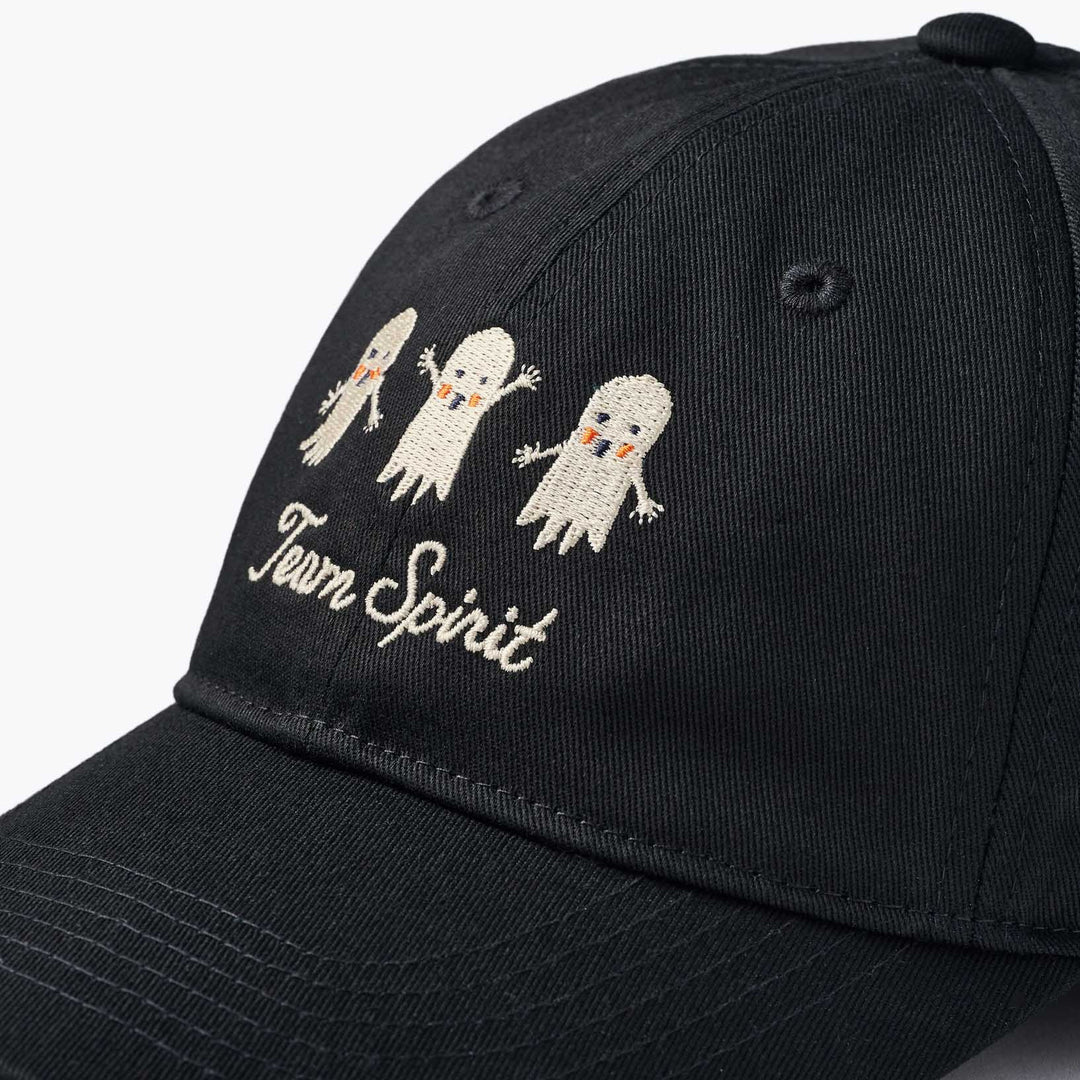 A close-up of a black baseball cap featuring embroidered white cartoon ghosts and the words 'Team Spirit' on the front panel.