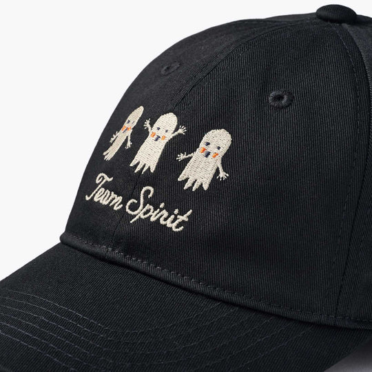 A close-up of a black baseball cap featuring embroidered white cartoon ghosts and the words 'Team Spirit' on the front panel.