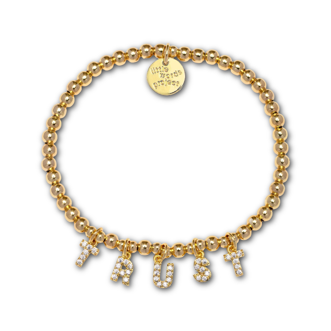 Gold beaded bracelet with gold and rhinestone letter-shaped charms spelling out "TRUST".