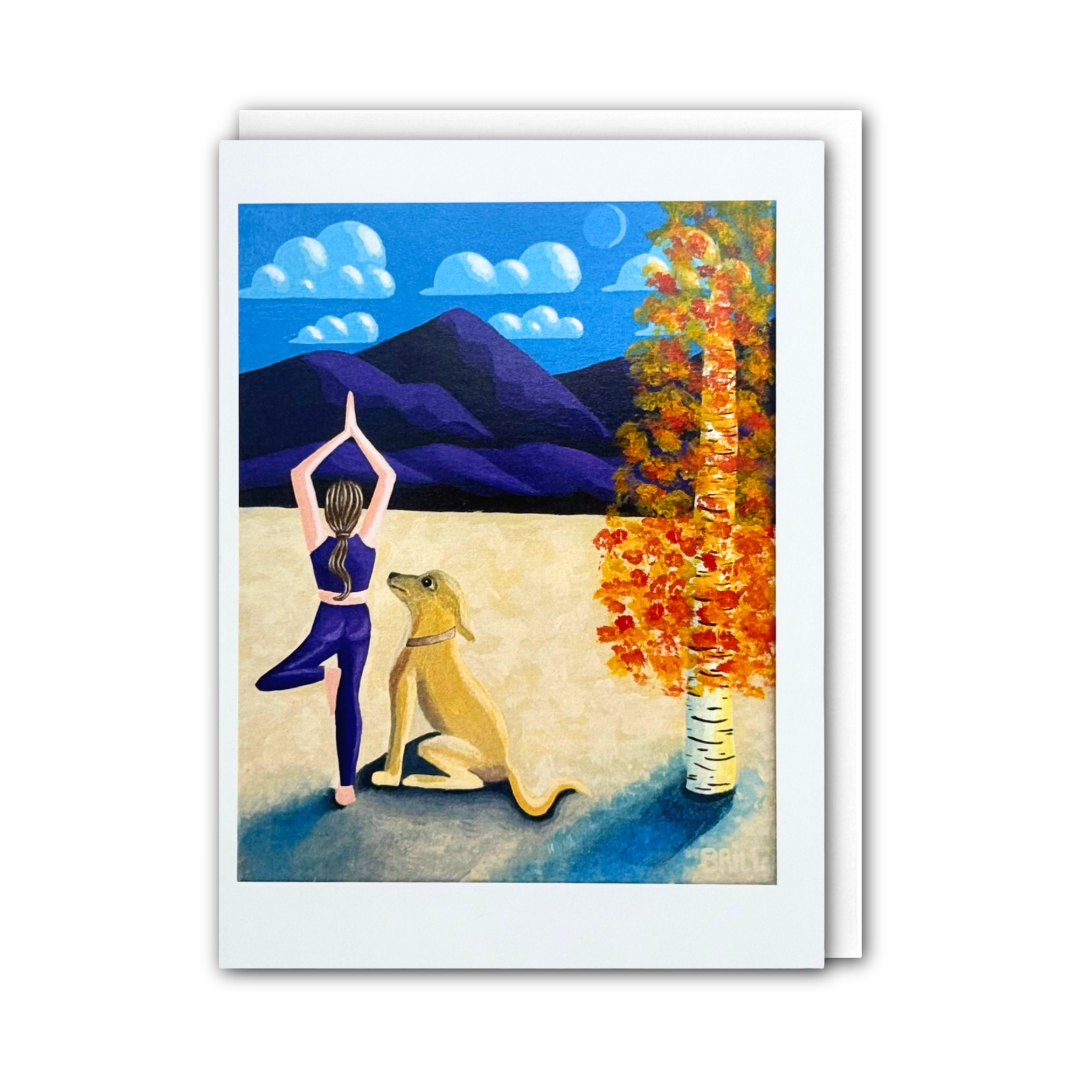 A greeting card with a white border, showing a painted scene of a woman in a yoga pose next to a dog, with mountains, clouds, and an autumn tree in the background.
